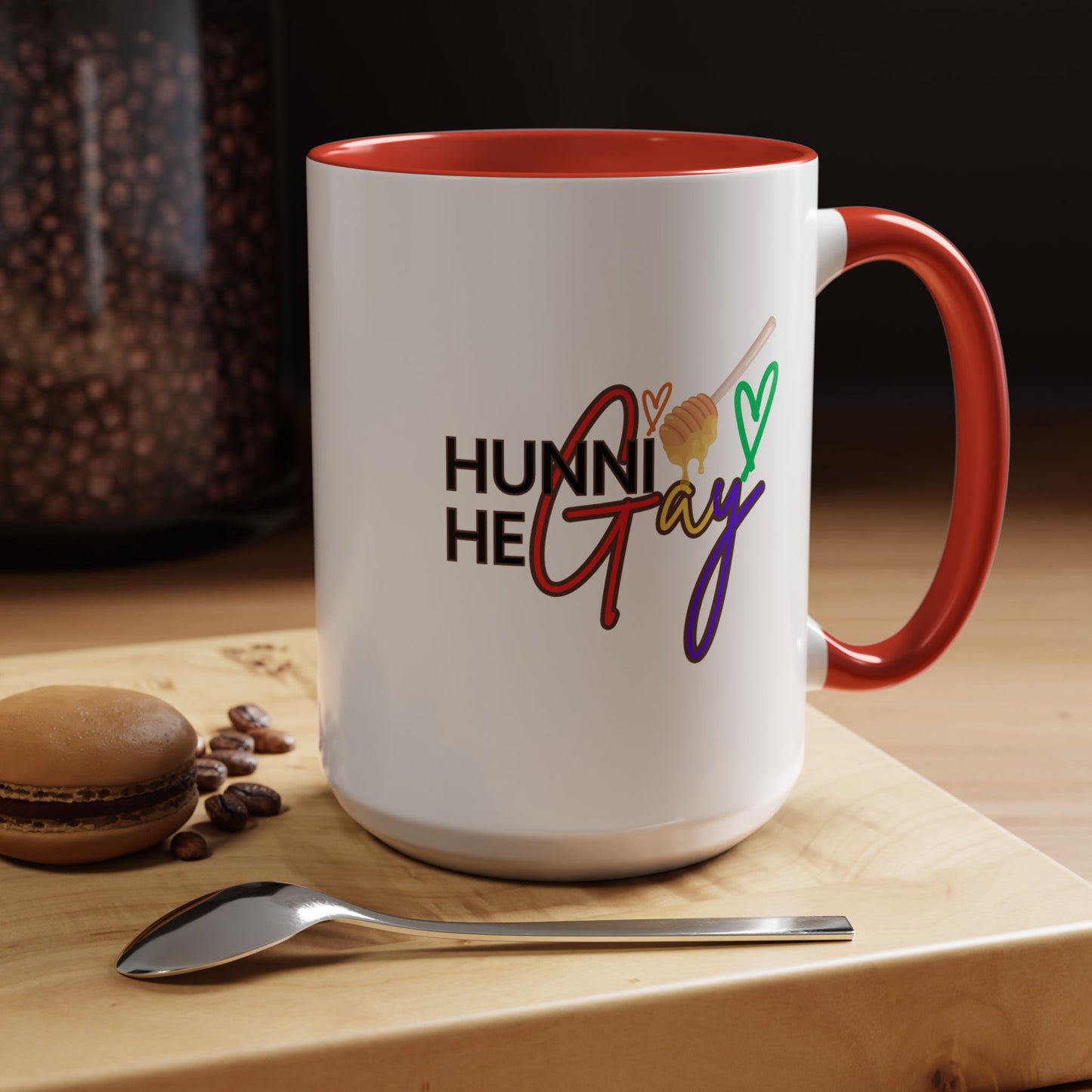White ceramic coffee mug featuring "Hunni He Gay" in bold rainbow text, accented with a striking red handle and rim for a fiery Pride statement.