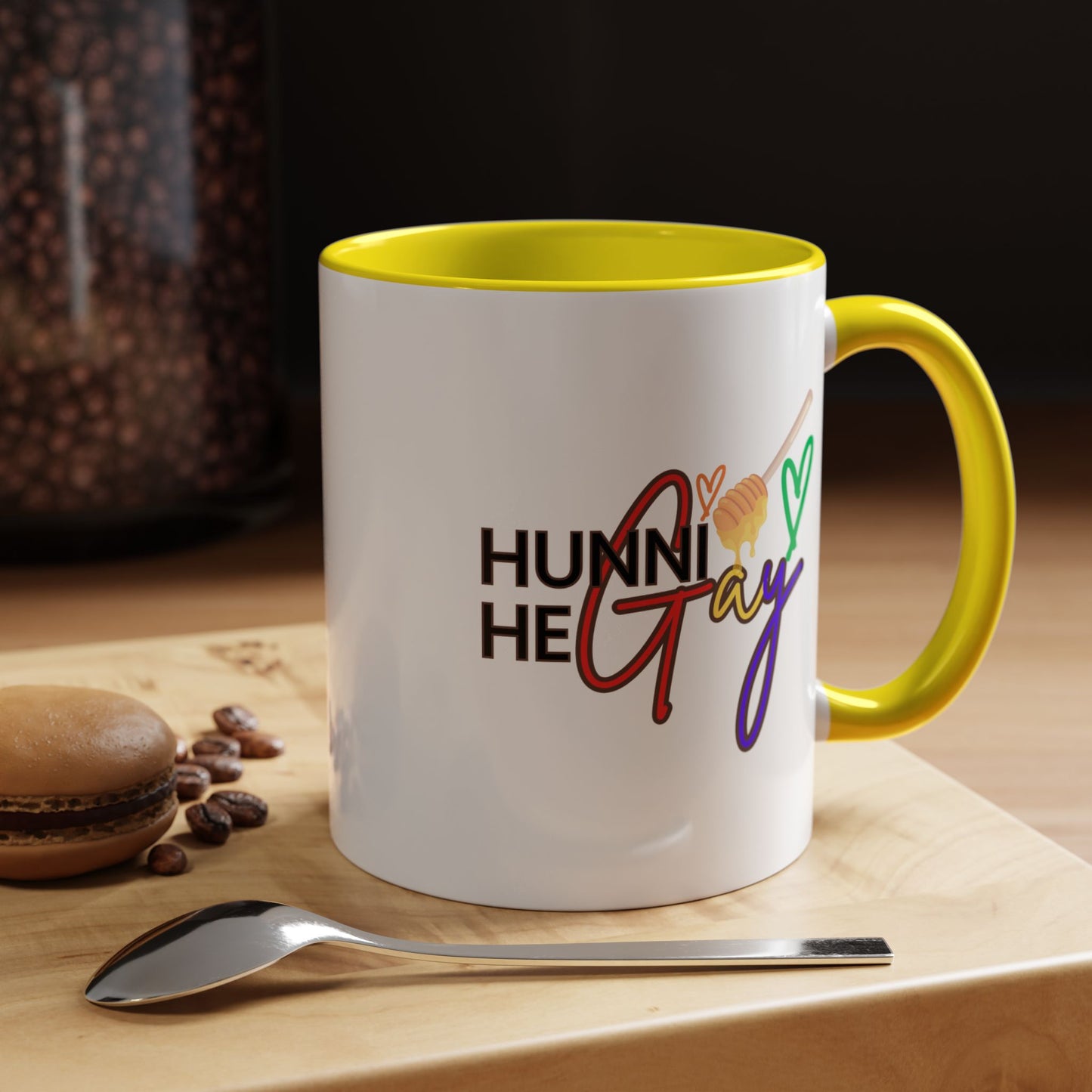White ceramic coffee mug featuring "Hunni He Gay" in playful rainbow lettering, complemented by a bright yellow handle and rim for a cheerful, Pride-inspired look.