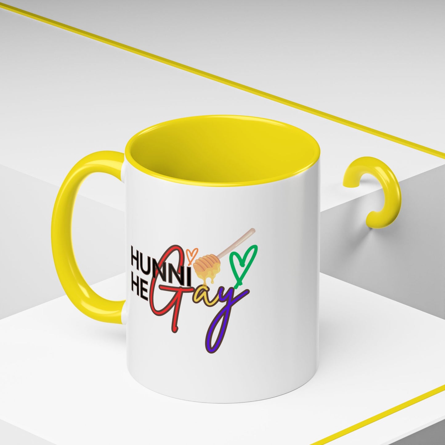 Close-up of a glossy Pride mug with "Hunni He Gay" in playful retro font, paired with a bright yellow interior and handle for a bold, energetic look.