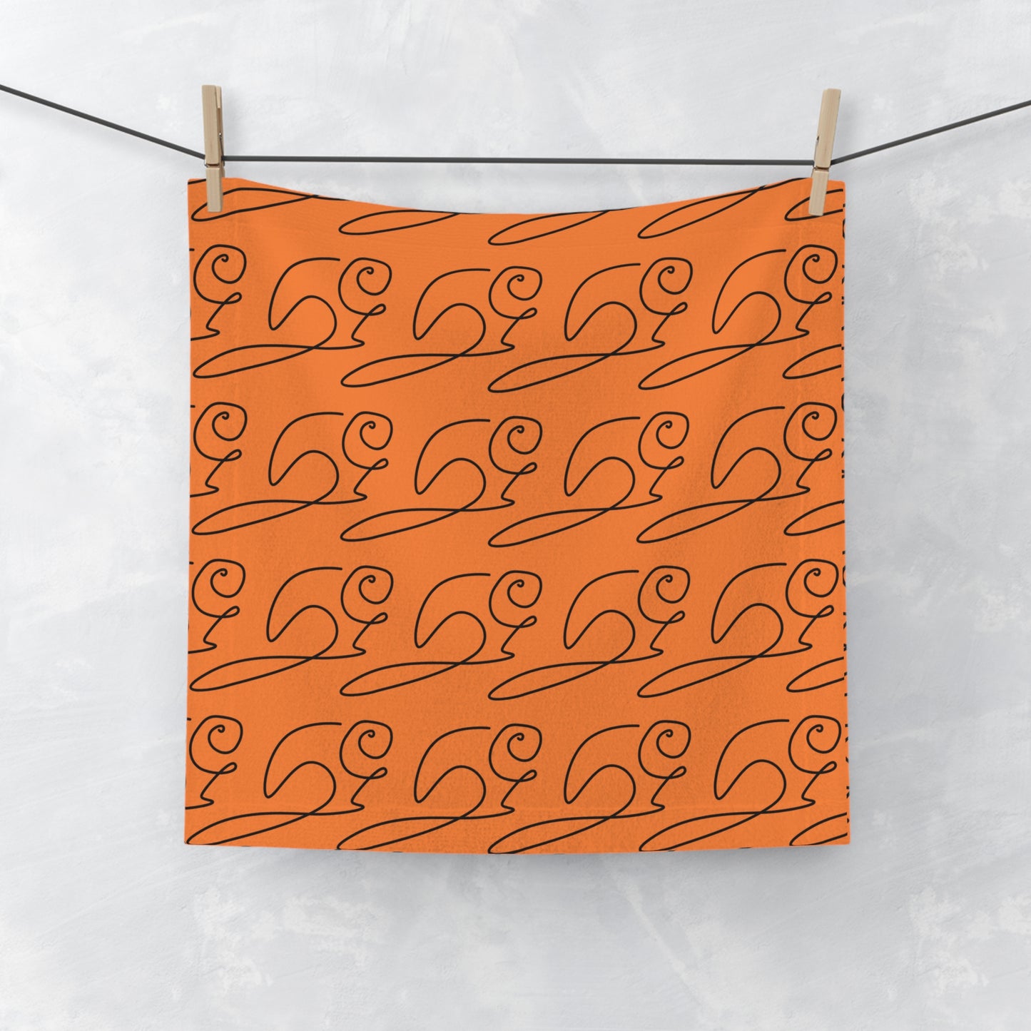 Orange face towel with elegant cursive lettering and subtle beaver motif, laid flat on white surface