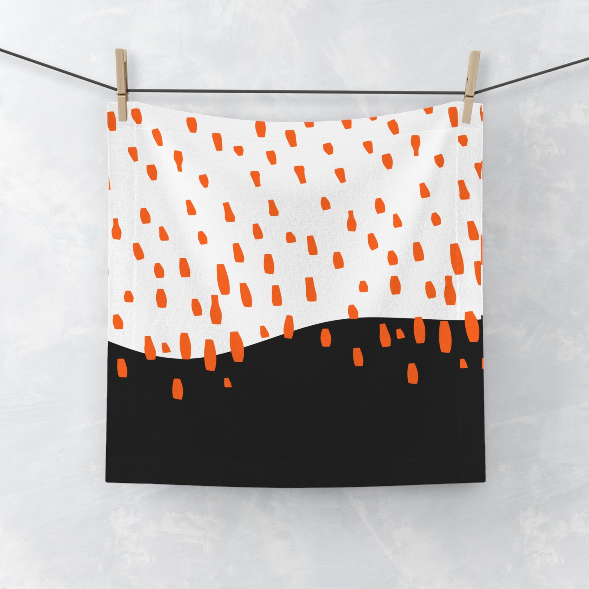Black face towel with orange rain pattern, laid flat on white backgroun