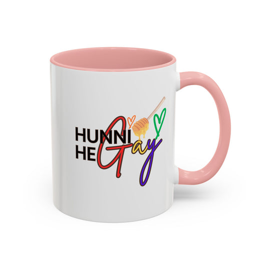 Glossy white ceramic mug featuring "Hunni He Gay" in playful rainbow typography, finished with a pastel baby pink handle and rim to add a charming Pride touch.