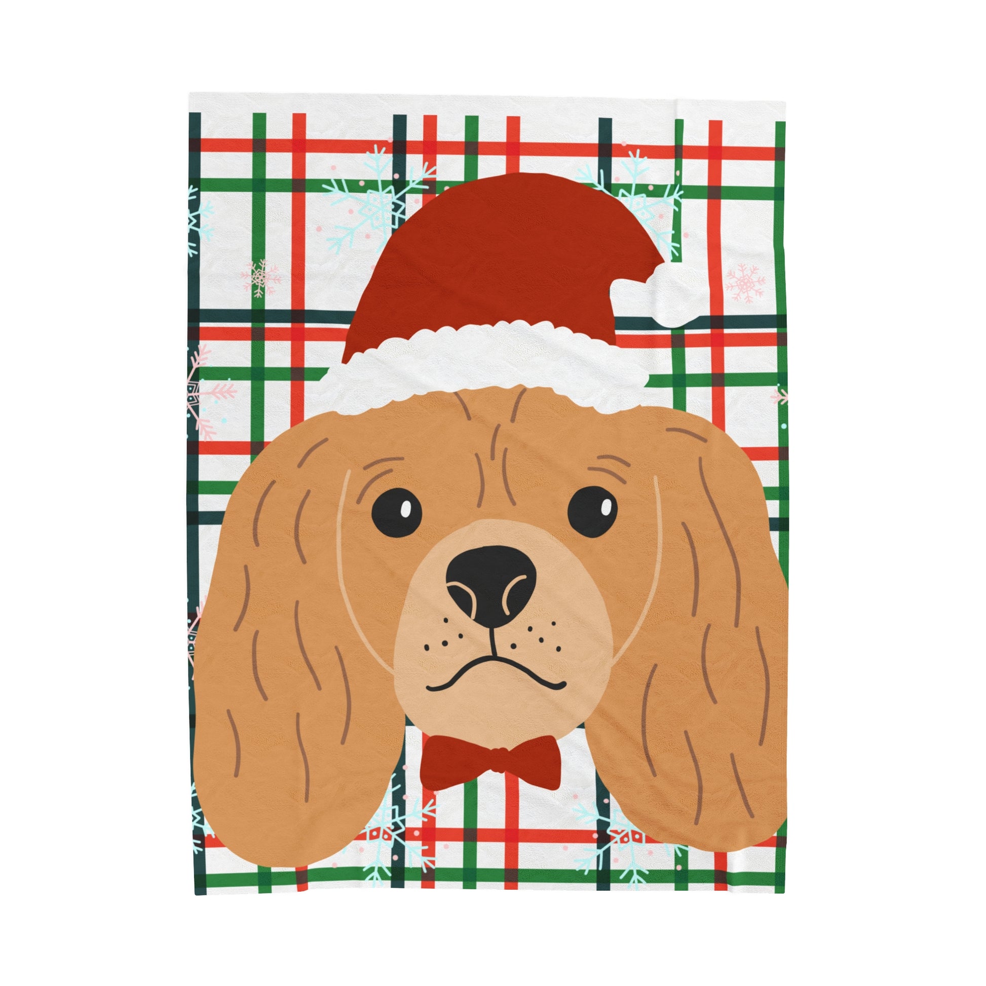 Flat lay of cozy holiday blanket with red and green plaid pattern and Santa Cocker Spaniel graphic on soft surface"