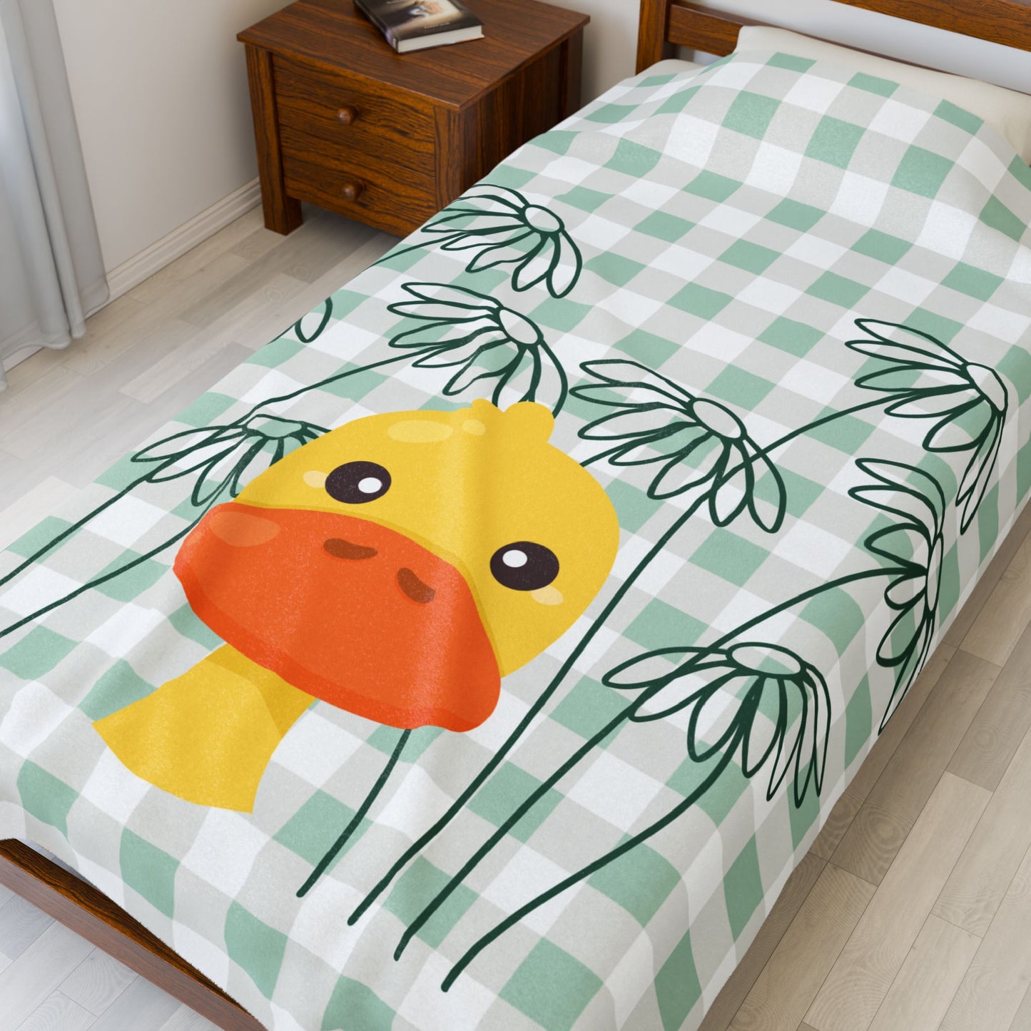 Close-up of plush blanket texture with whimsical duck and daisy design in soft green tones
