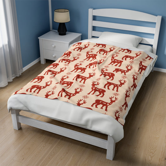 Rustic Christmas blanket with reindeer and snowflake cabin pattern draped over holiday couch with plaid pillows, stockings, and woodsy decor