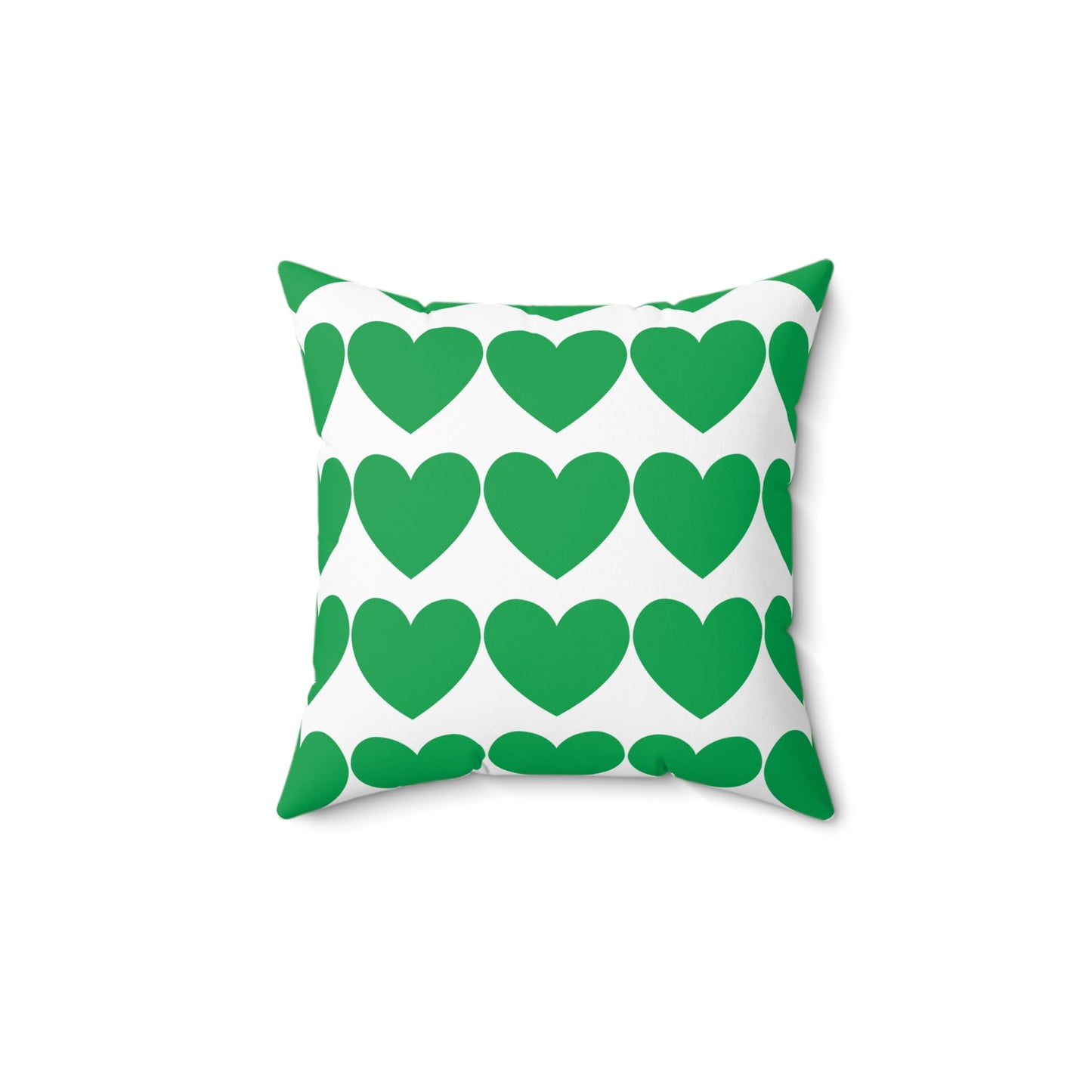 Green hearts pillow styled on a dorm bed with layered cozy blankets