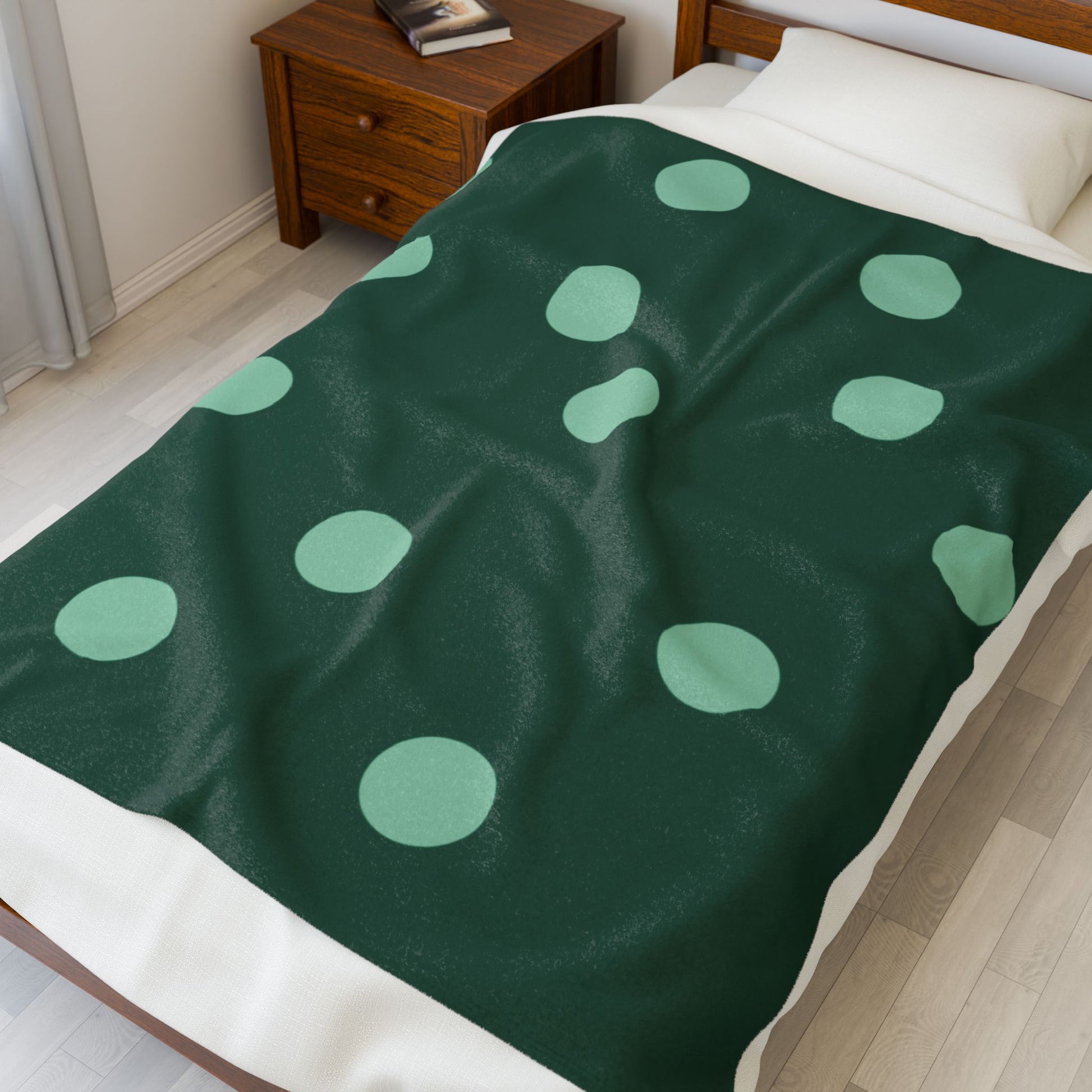 Folded plush blanket featuring mint and dark green polka dots for cozy comfort-core decor