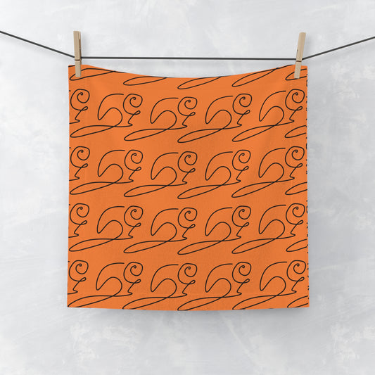 Orange face towel with elegant cursive lettering and subtle beaver motif, laid flat on white surface
