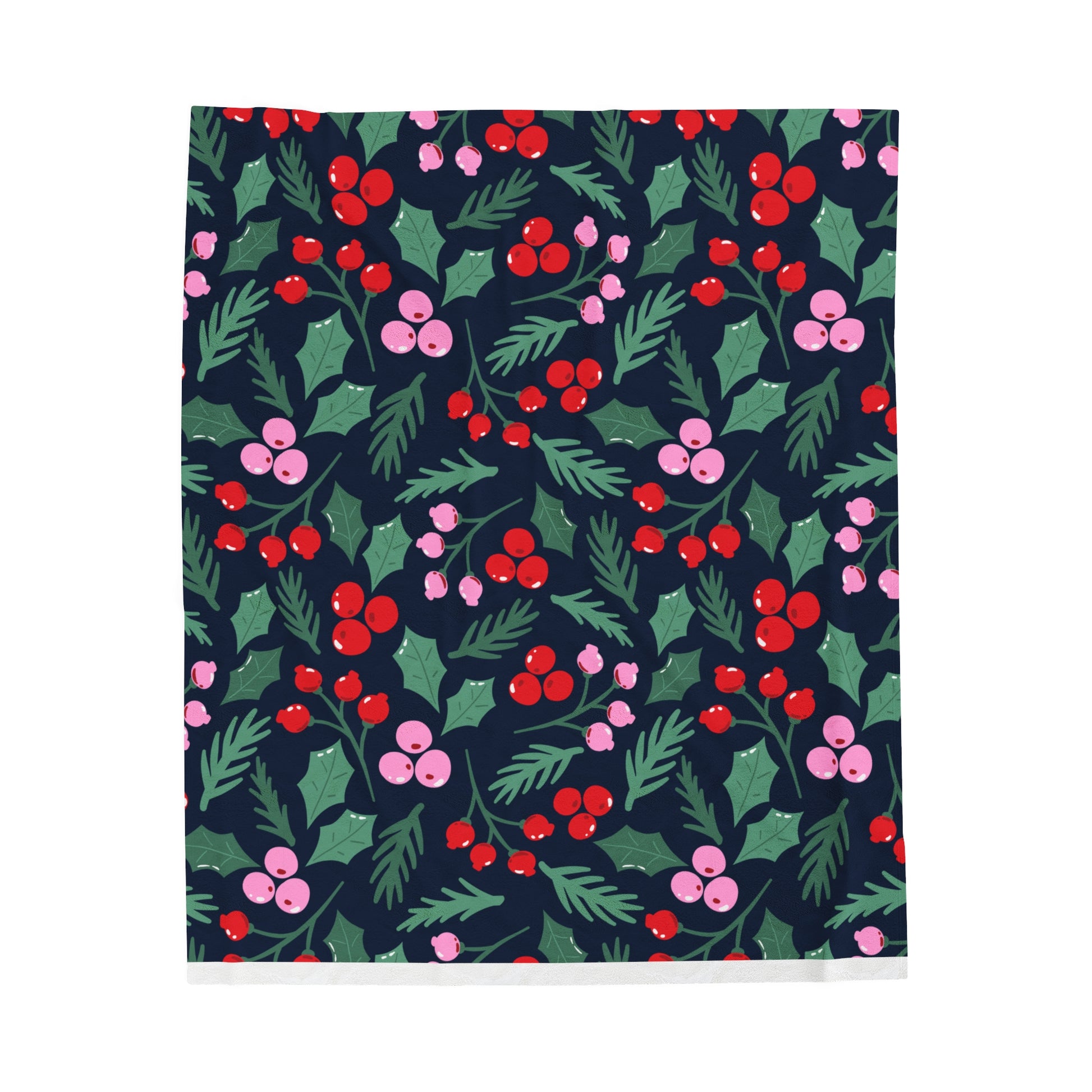 Flat lay of cozy holiday blanket with whimsical Christmas greenery pattern in pink, red, and green colors displayed on soft surface