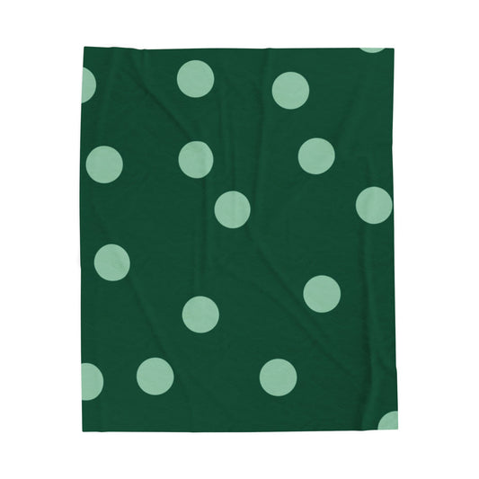 Dark and mint green plush throw blanket with polka dot pattern styled on retro dorm bed