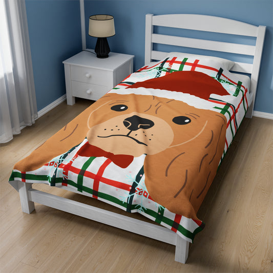 Large red and green plaid Christmas blanket featuring Cocker Spaniel in Santa hat draped over festive couch with pillows and holiday lights