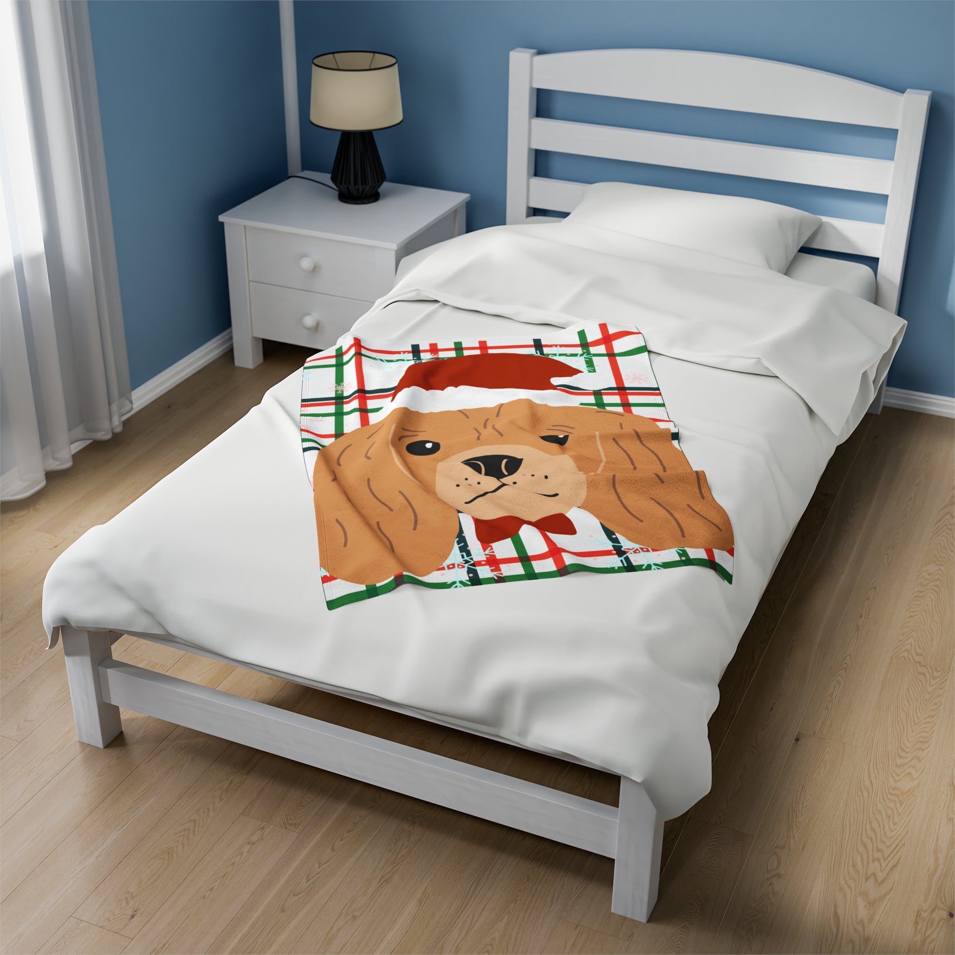 Small red and green plaid Christmas blanket featuring Cocker Spaniel in Santa hat draped over festive couch with pillows and holiday lights