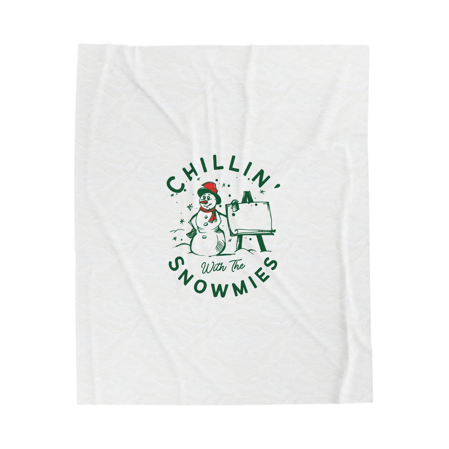 Flat lay of white holiday blanket featuring bold ‘Chillin with the Snowmies’ lettering, folded neatly on soft festive surface