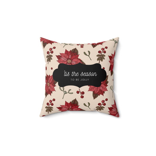 Flat lay of red floral holiday throw pillow featuring white ‘’Tis the Season’ text on soft fabric with Christmas greens