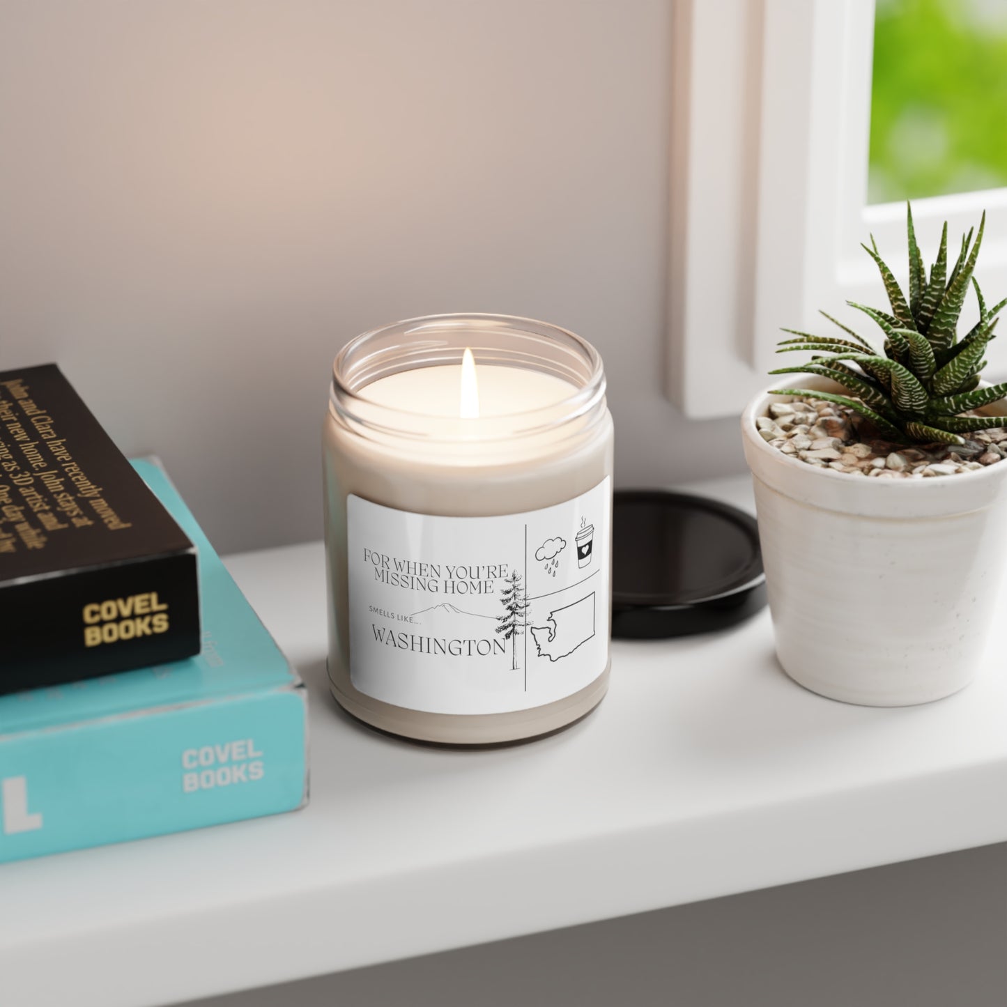 Missing Home – Washington candle burning on a windowsill beside pine branches and a ceramic mug, evoking cozy, nostalgic Pacific Northwest vibes.